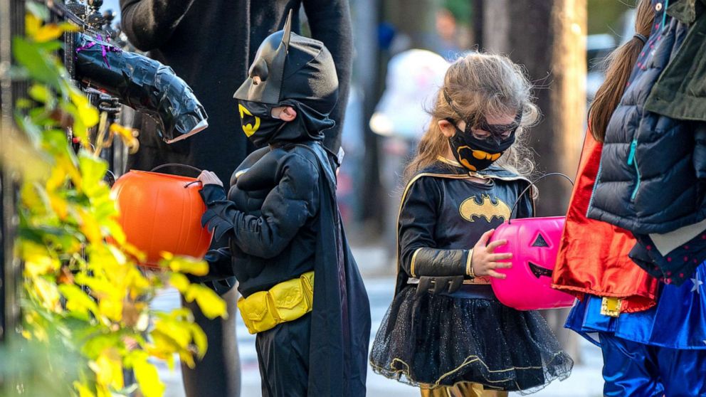 Trẻ em được thưởng thức đồ ăn vặt bằng máng kẹo trong khi chơi trò lừa hoặc đãi nhân dịp Halloween ở Woodlawn Heights vào ngày 31 tháng 10 năm 2020 ở Thành phố New York.