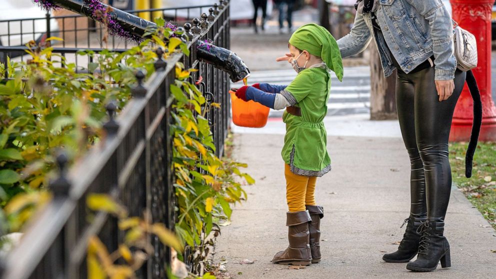 ẢNH: Trẻ em được thưởng thức đồ ăn vặt bằng máng kẹo trong khi chơi trò lừa hoặc đãi nhân dịp Halloween ở Woodlawn Heights vào ngày 31 tháng 10 năm 2020 ở Thành phố New York.